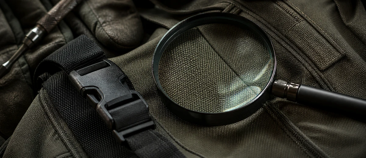 Magnifying glass inspecting the weave and hardware of an outdoor bag